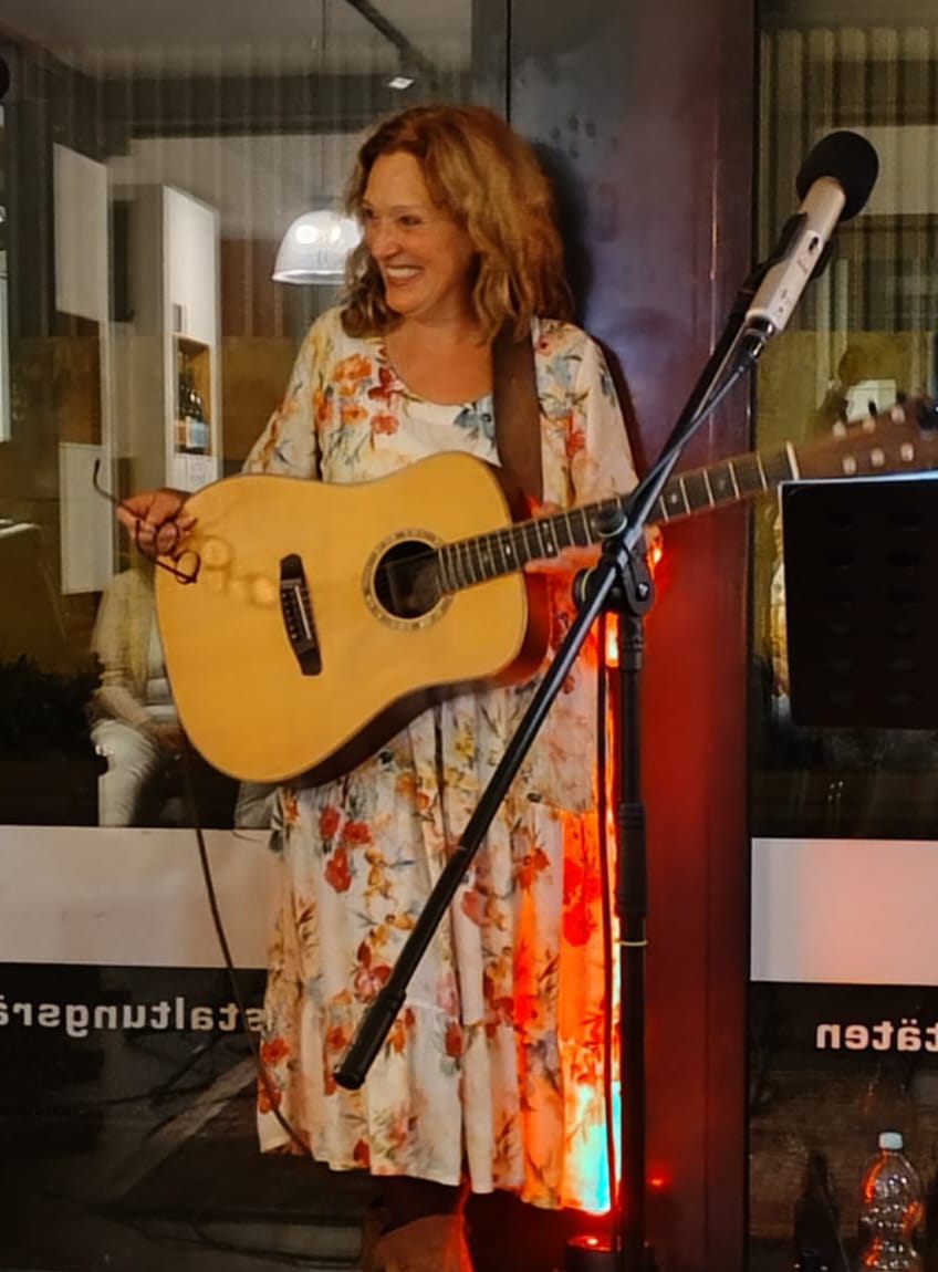 Inge Lorenzen mit der Gitarre in der Hand auf einer B&uuml;hne